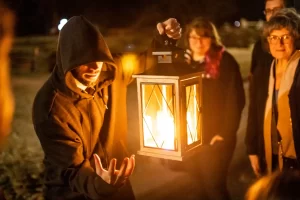 Man holding a lantern while giving a Ghost Tour