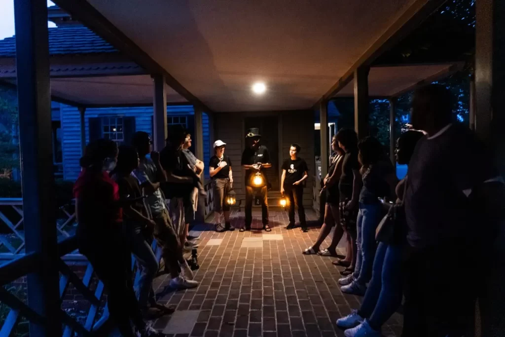 A group gathered around a tour guide holding a lantern